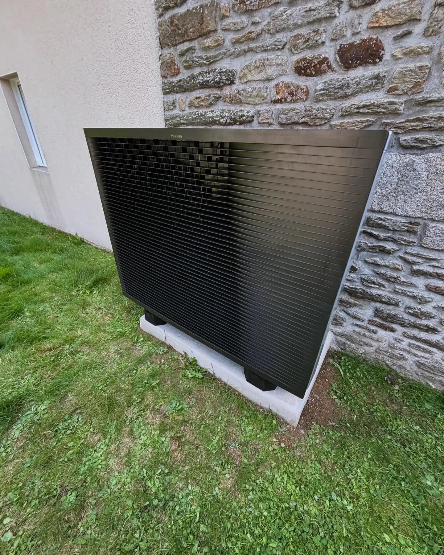 Pompe à chaleur installée contre un mur en pierre sur un chantier breton